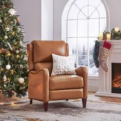 a living room with a christmas tree, fireplace and chair in front of the window