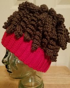 a crocheted hat on top of a mannequin's head in front of a door