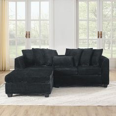 a black sectional sofa sitting on top of a white rug