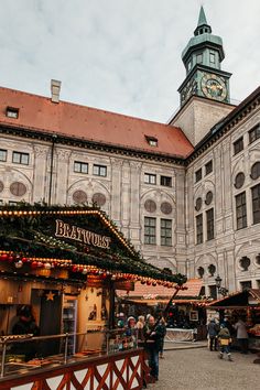 people are walking around in front of an old building with christmas decorations on the roof