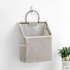 a bag hanging on the wall next to a potted plant and an air freshener dispenser