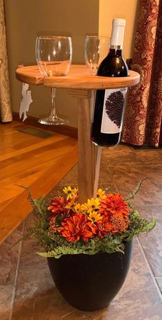 a bottle of wine sitting on top of a wooden table next to a vase filled with flowers