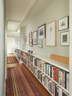 a long bookshelf filled with lots of books on top of a wooden floor