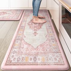 a woman standing on top of a pink rug in a kitchen next to an oven