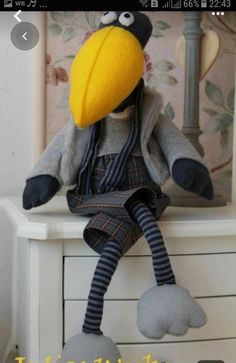 a stuffed bird sitting on top of a white dresser