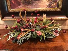 an arrangement of antlers, berries and greenery on a table in front of a painting