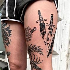 a woman's leg with tattoos on it and two knives in the middle of her thigh