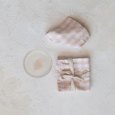 two napkins and a plate on a white surface with a light brown bow tie