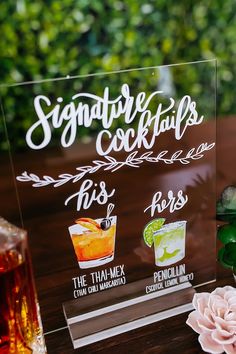 there is a sign that says signature cocktails on the table next to some drinks