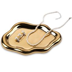 a gold tray with pearls on it and a chain hanging from the middle, in front of a white background