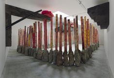 an art installation made out of rocks and wood sticks in a room with white walls