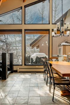 a dining room table and chairs in front of large windows