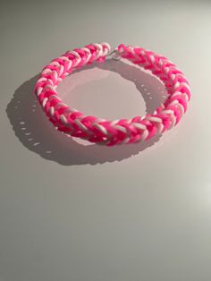 two pink and white braided bracelets sitting on top of a table