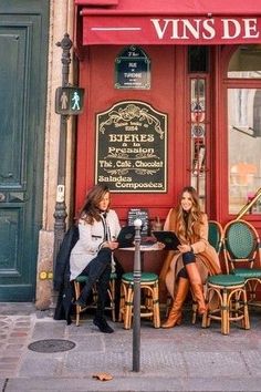 two women sitting at a table in front of a restaurant