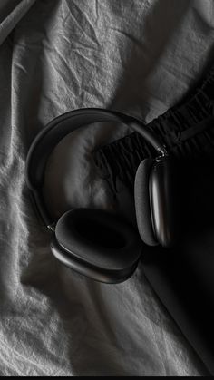 black headphones laying on top of a white sheet