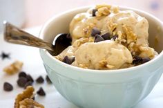 a bowl filled with ice cream covered in chocolate chips and nuts next to a spoon