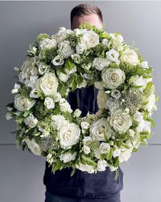 a man holding a wreath with white flowers