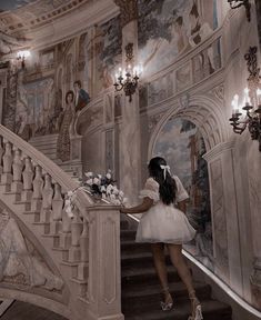 a woman in a white dress is walking down the stairs