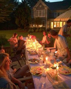 a group of people sitting around a table with food and candles in front of them