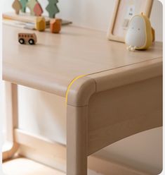 a wooden table with toy cars on it and a framed photo in the back ground