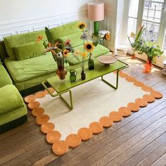 a living room with green couches and sunflowers in vases on the coffee table