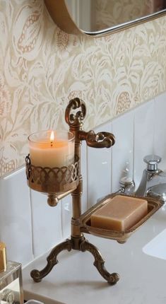 a candle that is sitting on top of a stand in front of a bathroom sink