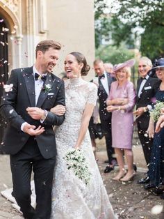 a bride and groom are surrounded by confetti as they walk down the street