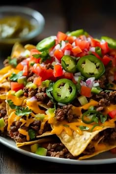 a white plate topped with nachos covered in cheese and toppings next to salsa