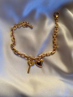 a gold heart and key bracelet on a white satin