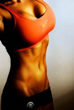 a woman in an orange sports bra top flexing her muscles