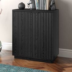 a black cabinet sitting on top of a hard wood floor next to a vase filled with flowers