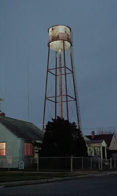 an old water tower sits in the middle of a neighborhood at night with no one around it