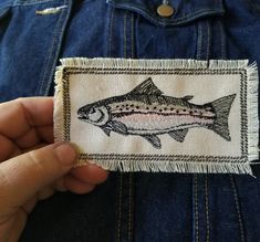 a person holding up a patch with a fish on it