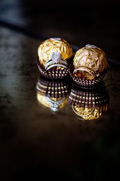 two gold rings sitting on top of a black table next to each other and reflecting in the water