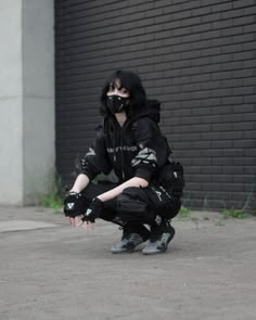 a person kneeling down on the ground wearing black clothing