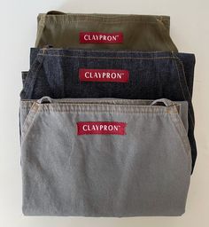 three pairs of jeans with the name clayron in red on them, stacked together