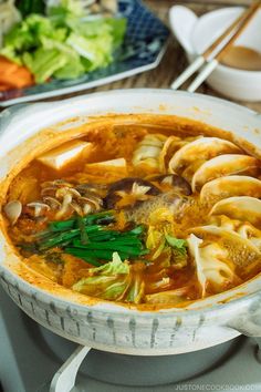 a bowl filled with soup and vegetables on top of a stove