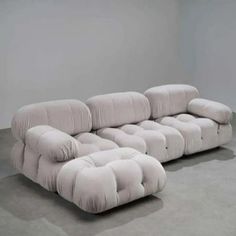 a large white couch sitting on top of a cement floor next to a gray wall