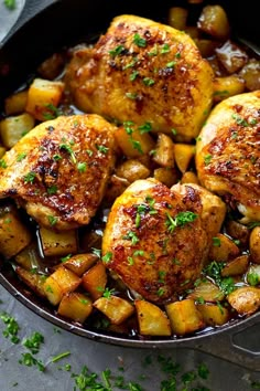 chicken and potatoes in a skillet with parsley sprinkled on the side