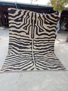 a zebra print rug is on the ground in front of a man standing next to it