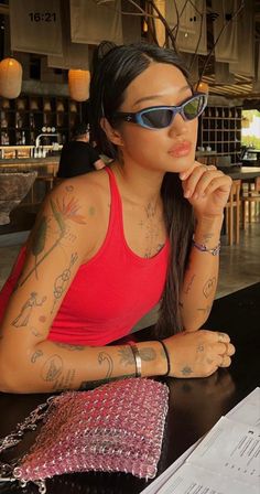 a woman sitting at a table with tattoos on her arm