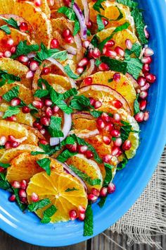 a blue plate topped with orange slices and pomegranate