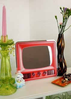 a red microwave sitting on top of a white table next to a vase with flowers