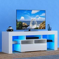 a flat screen tv sitting on top of a white entertainment center next to a blue wall