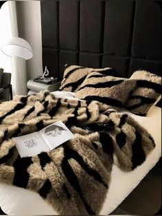 a bed with black and white furs on top of it next to a lamp