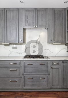 a kitchen with gray cabinets and marble counter tops