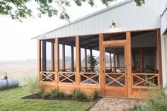 a screened porch in front of a white building with wooden railings and glass doors