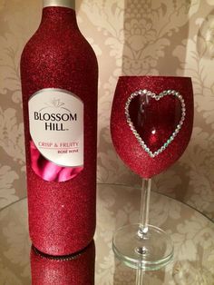 a red wine bottle with a heart on it next to a glass filled with liquid