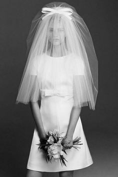 black and white photograph of a woman wearing a wedding dress with a veil over her head