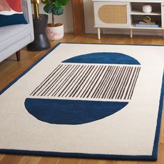 a blue and white area rug with an abstract design on the floor in front of a couch